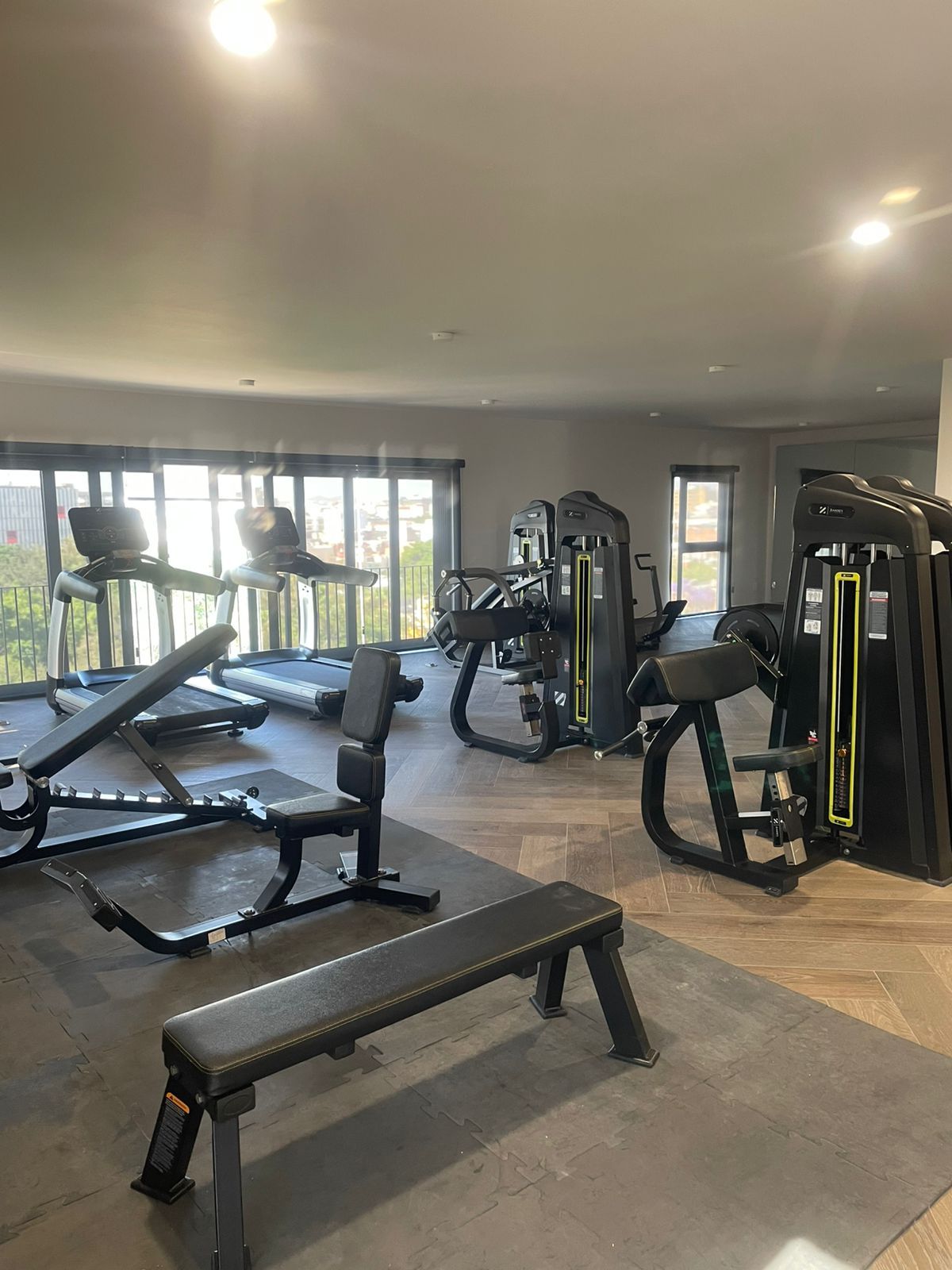 A gym with treadmills, weight machines, and a bench.