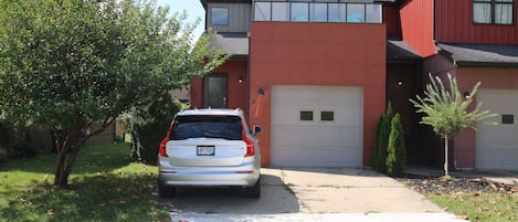 A modern two-story house with a garage, a driveway, and a tree in the front yard.