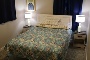 A neatly made bed with patterned bedding, two bedside lamps, and a nightstand with a drawer. - Great townhouse in Athens, 3 bedrooms, 5 beds, garage, Wi-Fi, bike path (Athens)