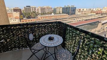 Un balcone con tavolo e sedie, un pavimento decorato e vista sulla città, con edifici e un ponte.