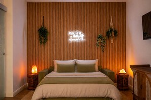 A bedroom with a wooden slat wall, a bed with green bedding, two bedside lamps, and hanging plants. - Private Suite across from Bari Centrale Station: Elegant and meticulously designed down to the last detail (Bari)