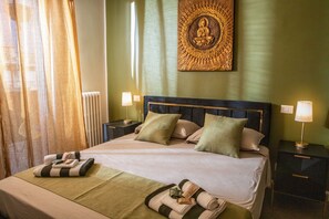 A hotel room with a bed, two bedside tables, a wall-mounted artwork, and a window with curtains. - Private Suite Facing Bari Centrale Station: Elegant and Meticulously Designed Down to the Last Detail (Bari)