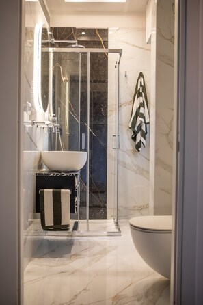 A modern bathroom with a glass-enclosed shower, a white sink, and a large toilet. - Private Suite across from Bari Centrale Station: Elegant and meticulously designed down to the last detail (Bari)