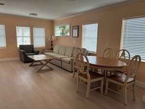 A living room with a sofa, a dining table with chairs, and a patterned armchair.