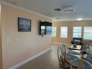 A dining area with a table, chairs, and a television mounted on the wall.
