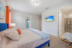 A bedroom with a bed, a television, and a door leading to a bathroom. - 10BR near Disney, sleeps 28, pool, spa & theater (Kissimmee)
