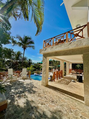 A resort with a pool, outdoor seating, and palm trees.