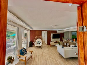 A spacious living area with a large TV, a wicker chair, and a sofa.