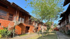 A brick building with multiple balconies and a central tree. - Ap p/ família, 3 quartos, 5min da praia (Ubatuba)