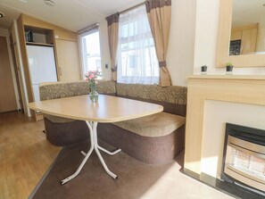 A compact living space with a round table, a sofa, a kitchenette, and a fireplace. - Sennen Sunset (Penzance)
