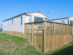 A mobile home with a fenced yard, a satellite dish, and a clear blue sky. - Sennen Sunset (Penzance)