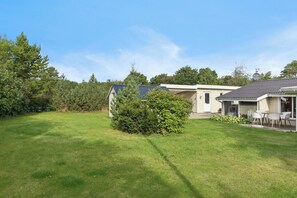 Ein Wohnhaus mit gepflegtem Rasen, einer Antenne und einer kleinen Terrasse.