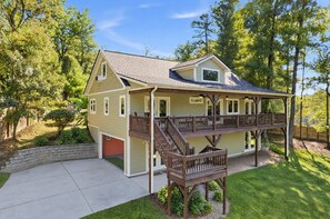 A two-story house with a covered porch and a deck. - Modern Farmhouse w Game Room Near Asheville! (Fairview)