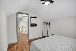 A bedroom with a bed, a ceiling fan, a mirror, and a black clothes rack. - Modern Farmhouse w Game Room Near Asheville! (Fairview)