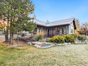 A two-story house with a sloped roof, a front porch, and a landscaped garden with a stone pathway. - Cozy Donnelly Retreat Near Boulder Creek | Wood Stove & Garage (Donnelly)