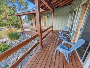 A wooden deck with chairs and a small table, surrounded by a wooden fence and a stone pathway. - Cozy Donnelly Retreat Near Boulder Creek | Wood Stove & Garage (Donnelly)