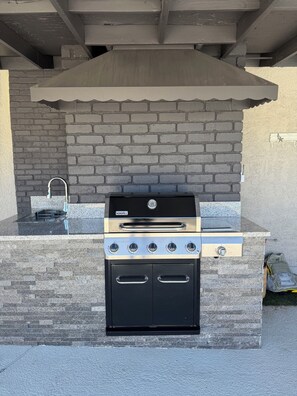 An outdoor kitchen with a built-in grill, a sink, and a stone countertop. - 10 Min to Strip & Fremont, Pool, Games & BBQ (Las Vegas)
