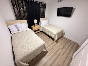 A hotel room with two beds, a TV, and a nightstand with a lamp. - 10 Min to Strip & Fremont, Pool, Games & BBQ (Las Vegas)