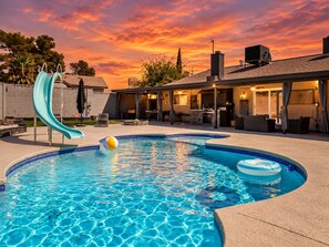 A swimming pool with a slide, a lounge area, and a covered patio with outdoor furniture. - 10 Min to Strip & Fremont, Pool, Games & BBQ (Las Vegas)