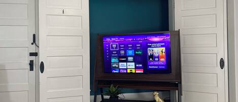 A room with a television on a stand, a potted plant, and a gold-colored statue.