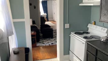 Een keuken met een fornuis, kastjes en een eethoek met een tafel en stoelen.