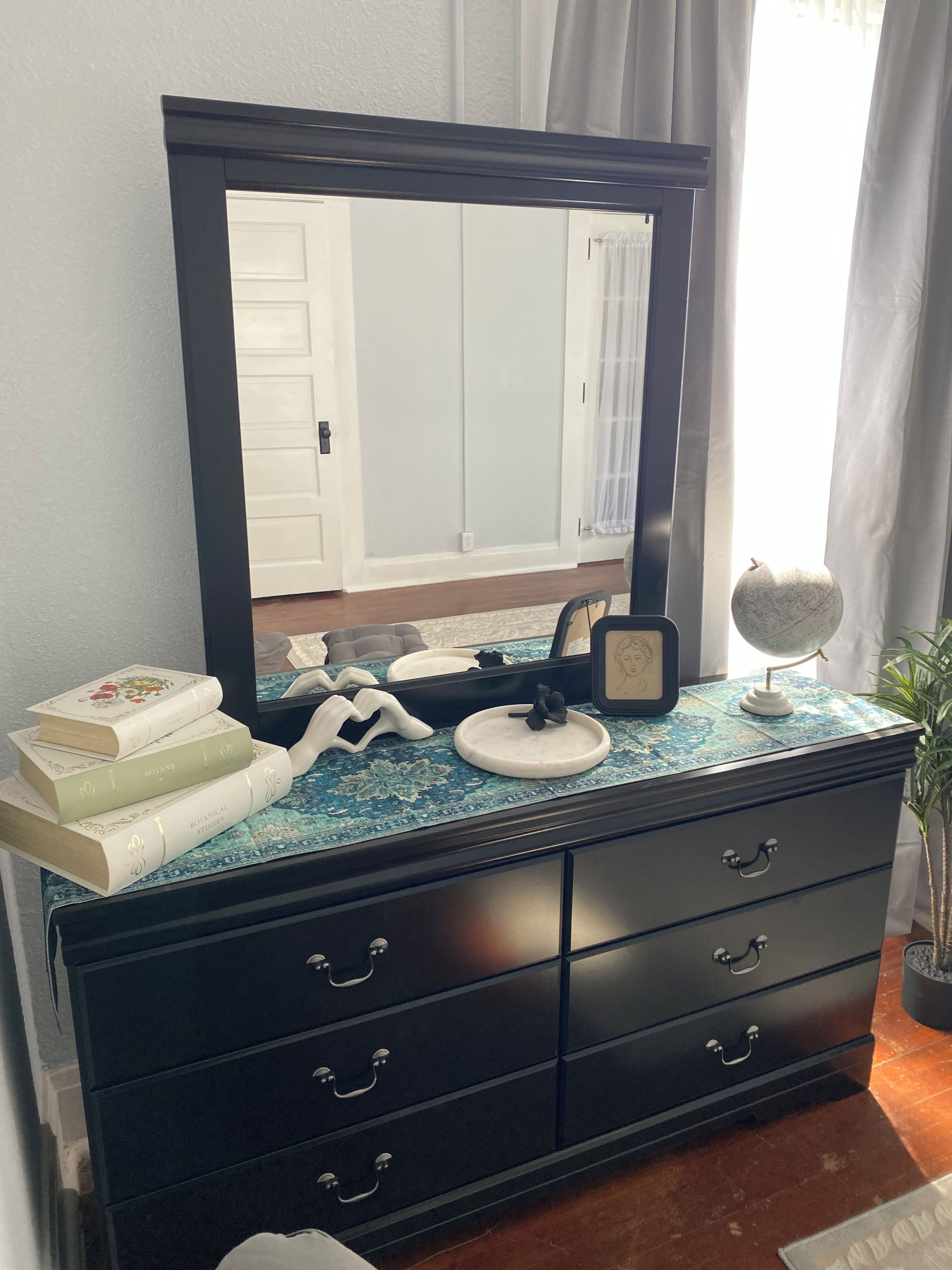 A dresser with a large mirror, a globe, and several books.