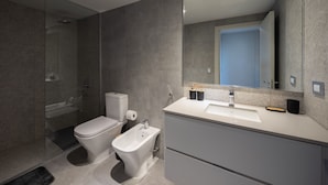 Un baño moderno con inodoro, bidé y un espejo grande.