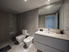 Een moderne badkamer met toilet, bidet en een grote spiegel.