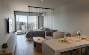 A modern living room with a sofa, coffee table, and a dining area with a table and chairs.