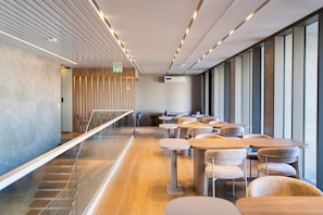 Een modern interieur met een lange gang, een zithoek met ronde tafels en een trap.