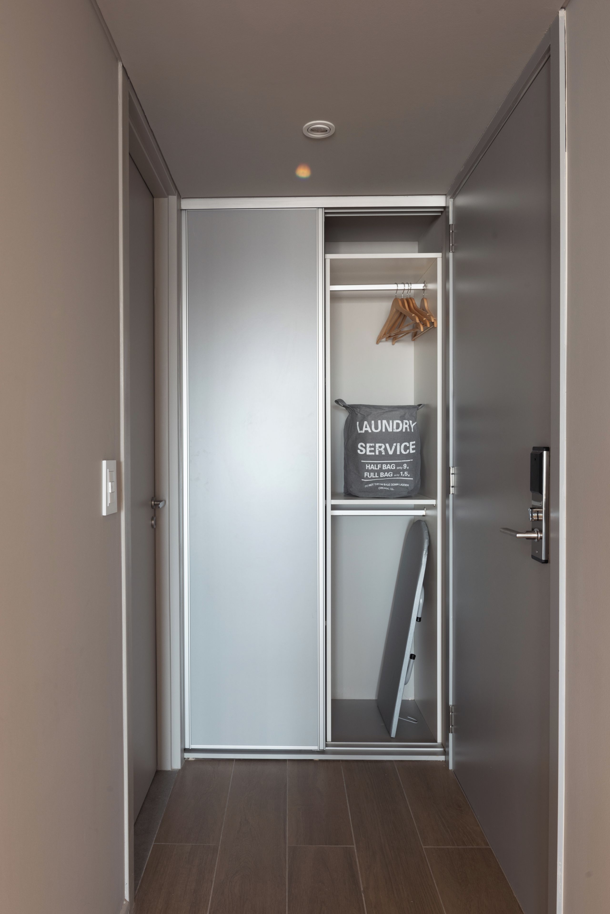 Un interior moderno con una puerta corredera que da a un área de lavandería, incluyendo un cartel con precios para bolsas pequeñas y grandes.