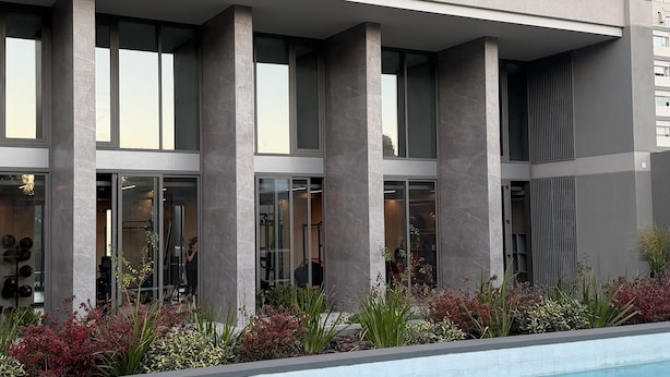 Un edificio moderno con piscina delantera, con varios balcones y ventanas amplias.