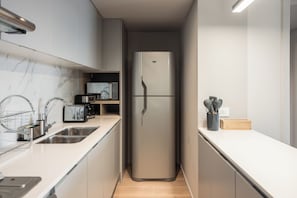 Een moderne keuken met roestvrijstalen apparatuur, een ingebouwde oven en een magnetron.