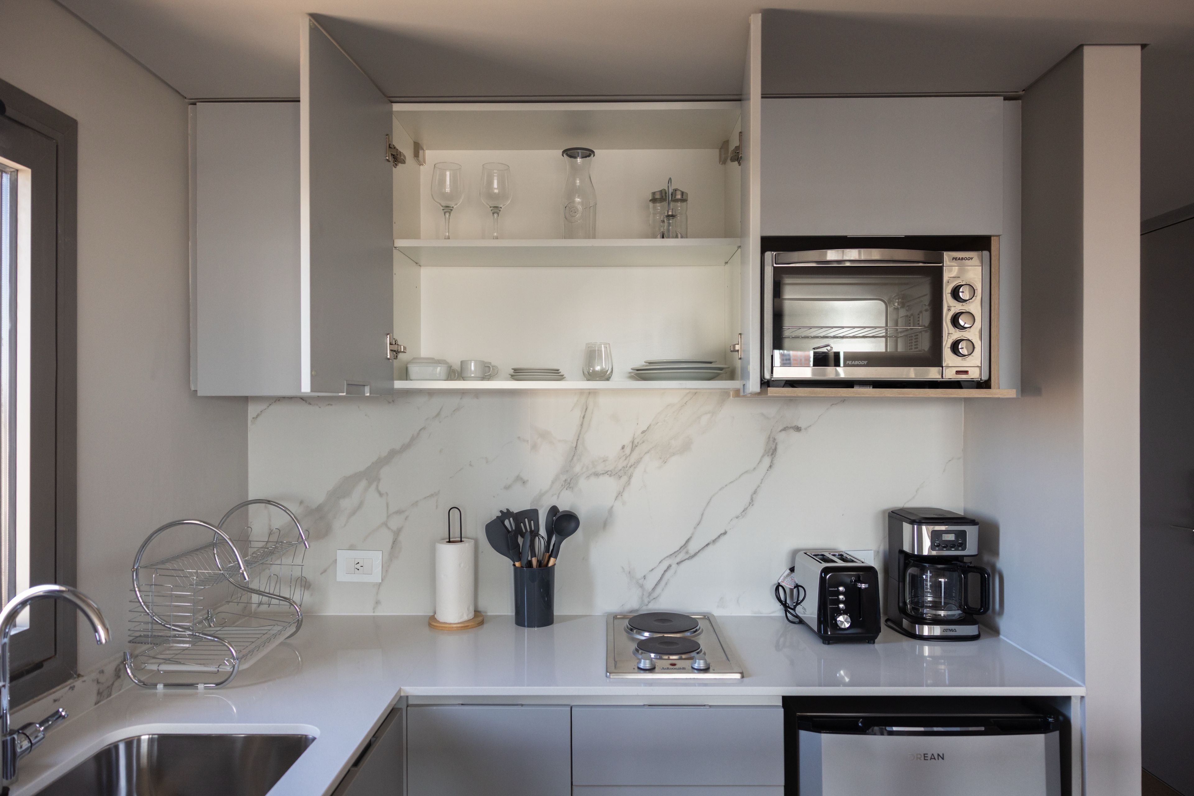 Una cocina moderna con microondas integrado, cafetera y tostadora.
