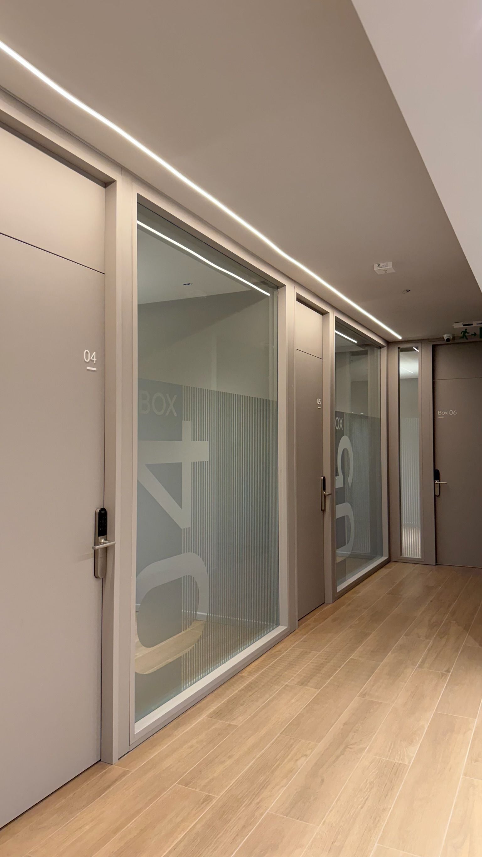 A hallway with sliding doors marked with room numbers, a modern design, and a wooden floor.