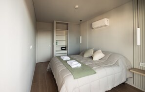 Un dormitorio con cama, mesita de noche, armario y radiador.