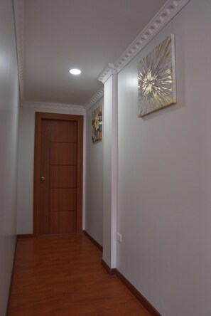 Ein Flur mit einer Holztür, einer Deckenleuchte und einer Wand mit einem dekorativen Gemälde.
