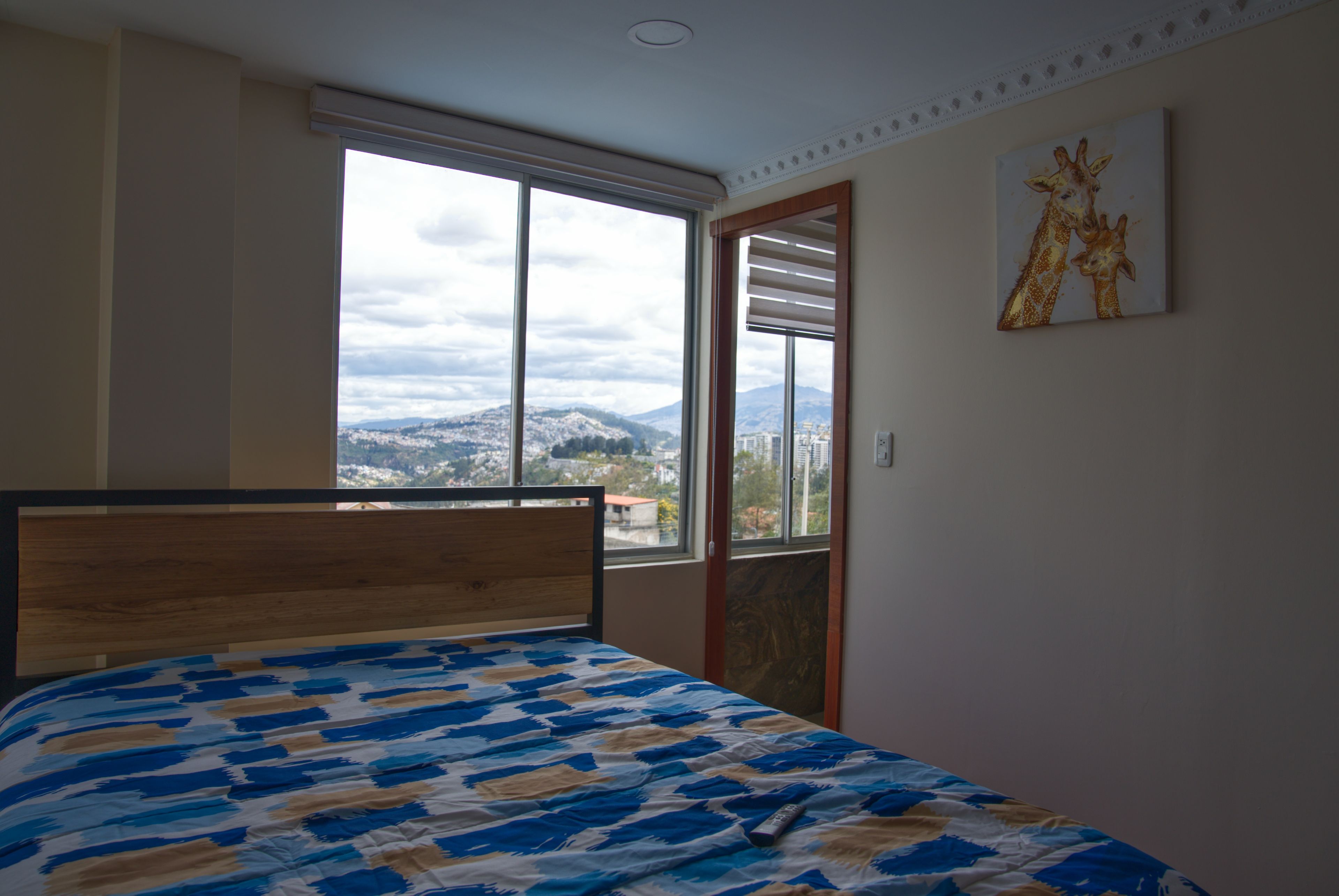 Ein Schlafzimmer mit einem Bett, einem Fenster mit Bergblick und einem Bild an der Wand.