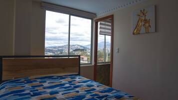 Ein Schlafzimmer mit einem Bett, einem Fenster mit Bergblick und einem Bild an der Wand.