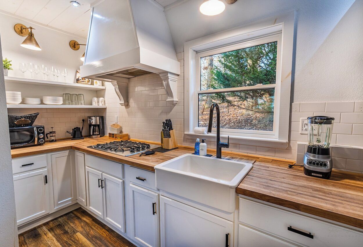 Una cucina moderna con mobili bianchi, un'ampia finestra e un piano cottura integrato.