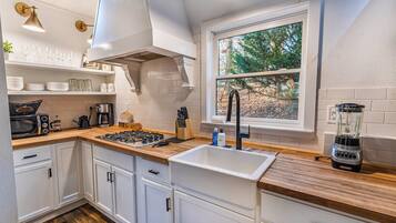 Una cucina moderna con mobili bianchi, un'ampia finestra e un piano cottura integrato.
