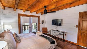 A bedroom with a bed, a television, a chair, and a table.