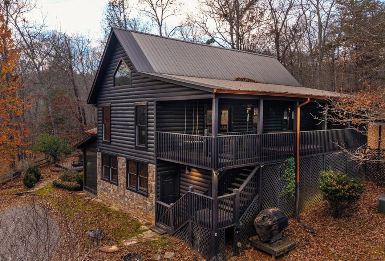 A log cabin with a balcony and a staircase leading to the entrance.
