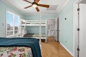 A room with bunk beds, a ceiling fan, and a view through a window. - Cakewalk𓇼Canal Front+Private Dock+Walk to Beach (Ocean Isle Beach)