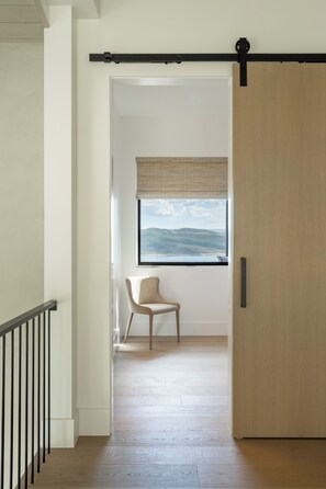 A room with a sliding door, a window with a view of the outdoors, a chair, and a wooden floor. - Deer Valley East Village - Mountain Views - Sleeps 12 4B/5.5B - Ski in Minutes (Daniel)
