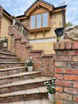 Una escalera de ladrillo que lleva a una casa con ventana de madera y pared de piedra.