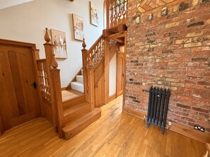 Una escalera de madera con un radiador y pared de ladrillo.