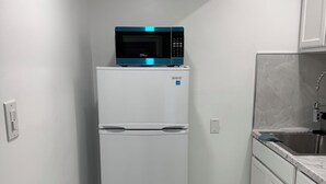 A compact kitchen with a white refrigerator, a microwave on top, and a sink with a marble countertop. - Private King Suite with Private Entrance & Parking in Hialeah (Hialeah)