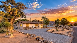 A residential area with houses, a gravel driveway, and a sunset. - Casa Sol, Fire Pit, Games, BBQ, Stargazing, More (Yucca Valley)