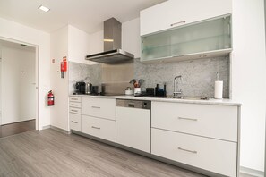 A modern kitchen with white cabinetry, a stainless steel range hood, a built-in oven, and a marble backsplash. - Top floor apartment in city center (Funchal)